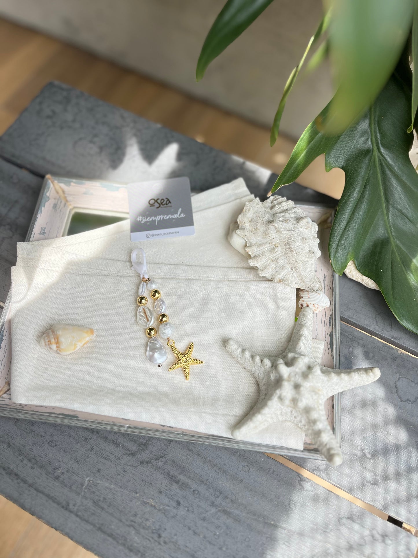 Llavero o charm en fantasía con perlas y dije de estrella de mar.