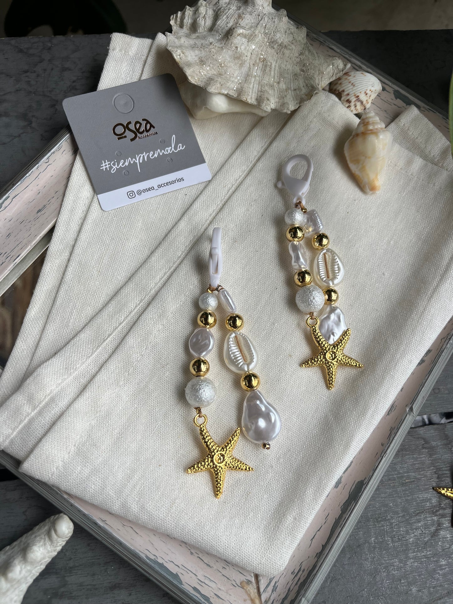 Llavero o charm en fantasía con perlas y dije de estrella de mar.